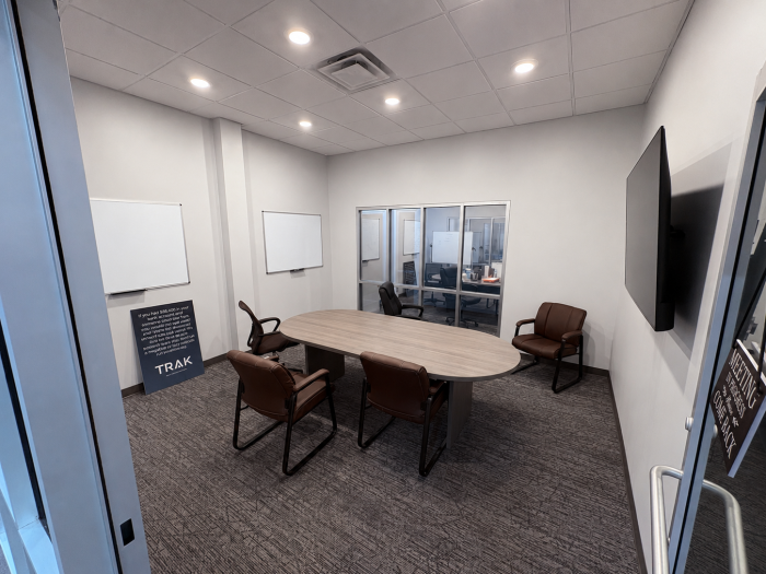 A conference room with a table, chairs, mounted TV, and whiteboards.